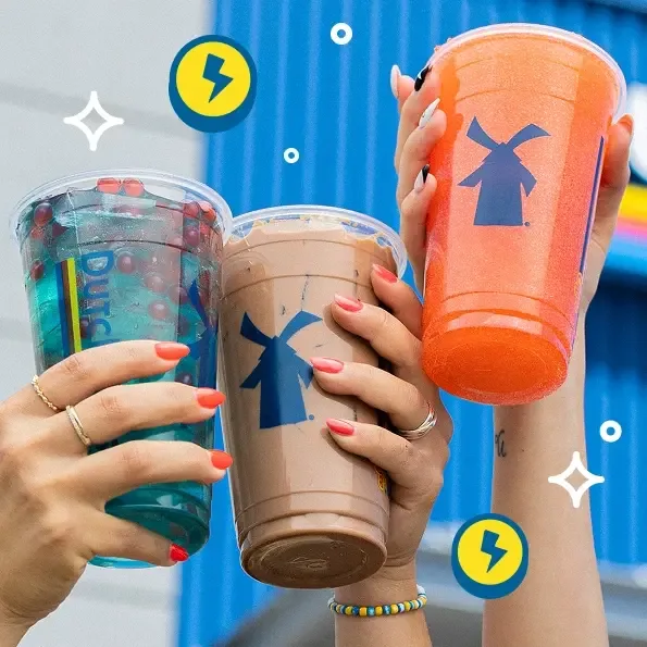 Hands holding three Dutch Bros coffee drinks in blue, brown and orange cups with windmill logos against a blue background.