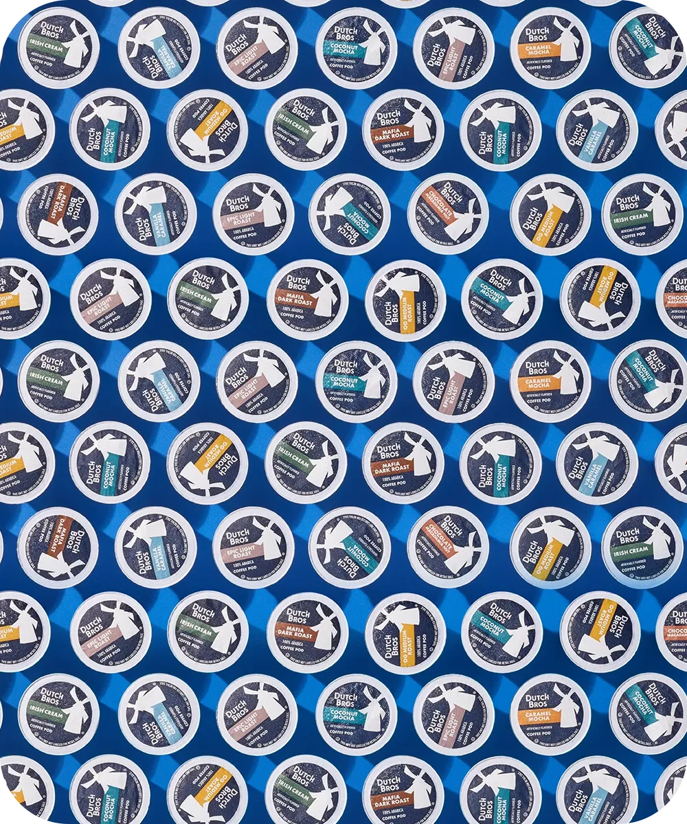 Array of Dutch Bros coffee pods in various flavors including Irish Cream, Coconut, and Dark Roast against blue background.