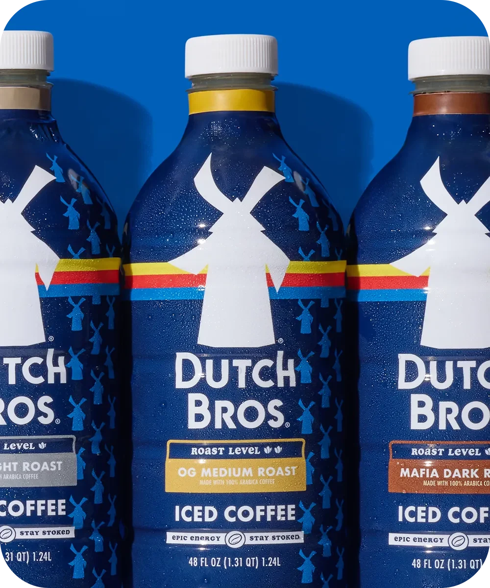 Three Dutch Bros bottled iced coffee drinks with blue packaging, featuring different roast levels against a blue background.