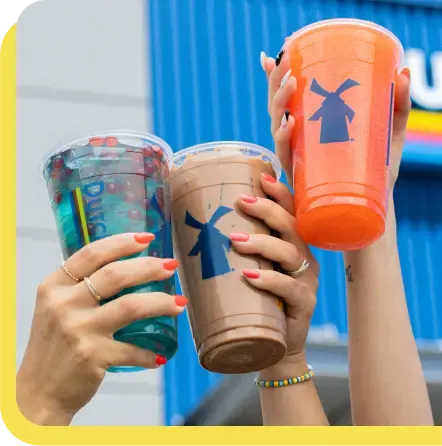 Three hands raising colorful Dutch Bros coffee cups with windmill logos against a blue background.